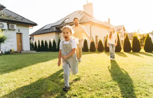 a child running on grass with a man and woman in the background