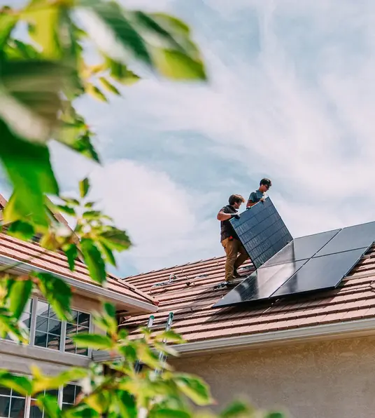 a couple of men installing solar panels on a roof
