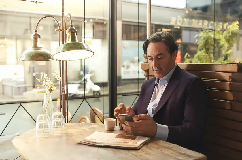 a man sitting at a table looking at his phone