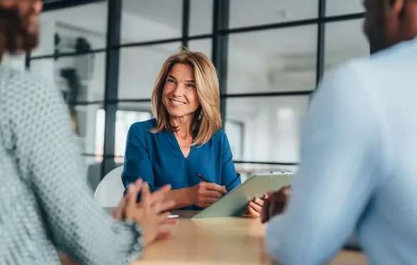 a woman smiling at a table with people sitting around it