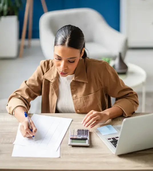 a woman sitting at a desk writing on a piece of paper