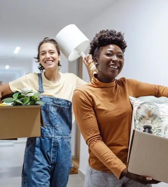 a couple of women carrying boxes and a plant