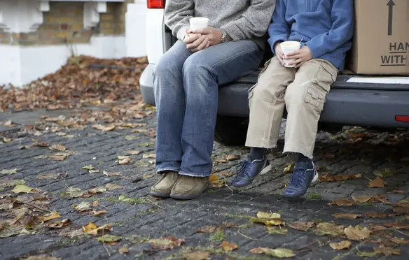 a man and child sitting on the back of a car