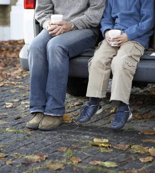 a man and child sitting on the back of a car