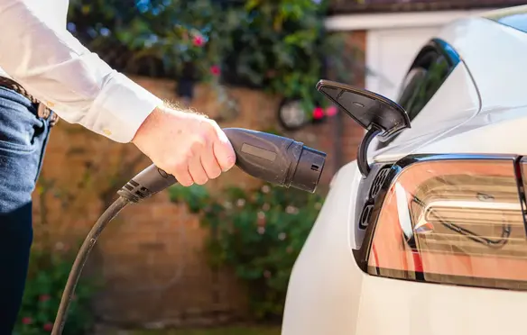 a person holding a power cord to a car