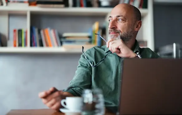 a man sitting at a table with a laptop and glasses