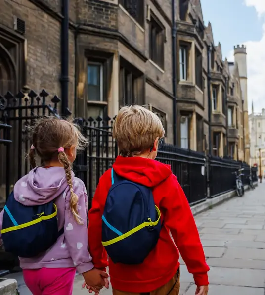 a boy and girl walking down a sidewalk
