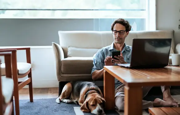 a man sitting on the floor with a dog and a laptop